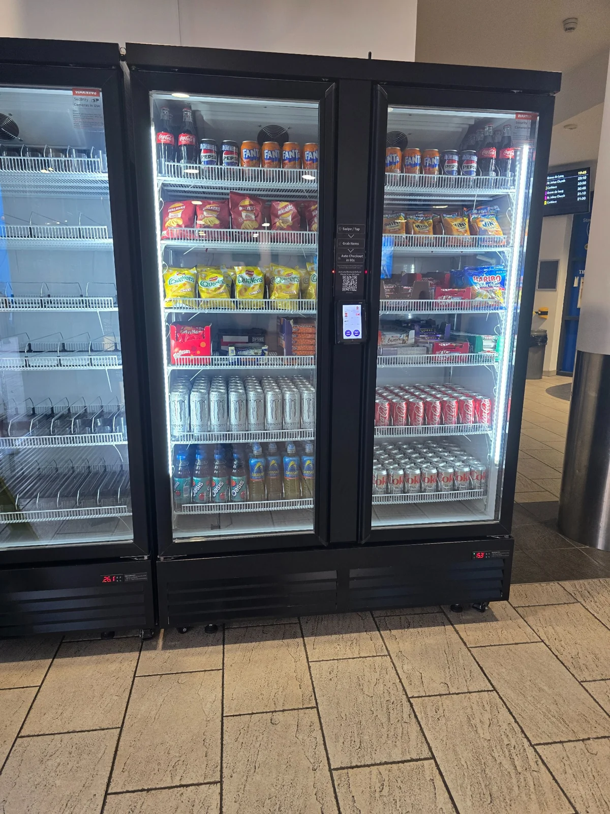 Installed smart cooler stocked with snacks and drinks behind glass doors